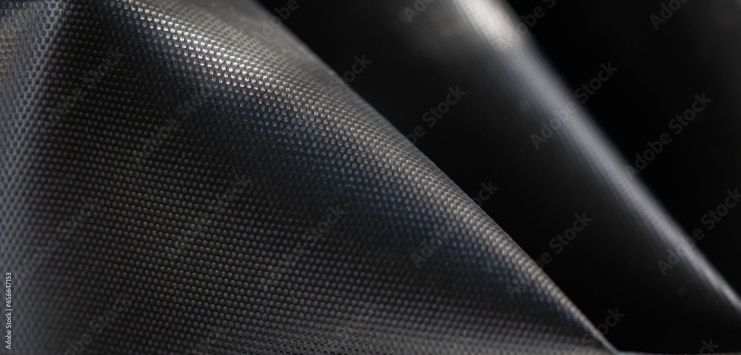 Close-up of a textured, black, pyramid-shaped foam acoustic panel with a grid-like surface pattern.